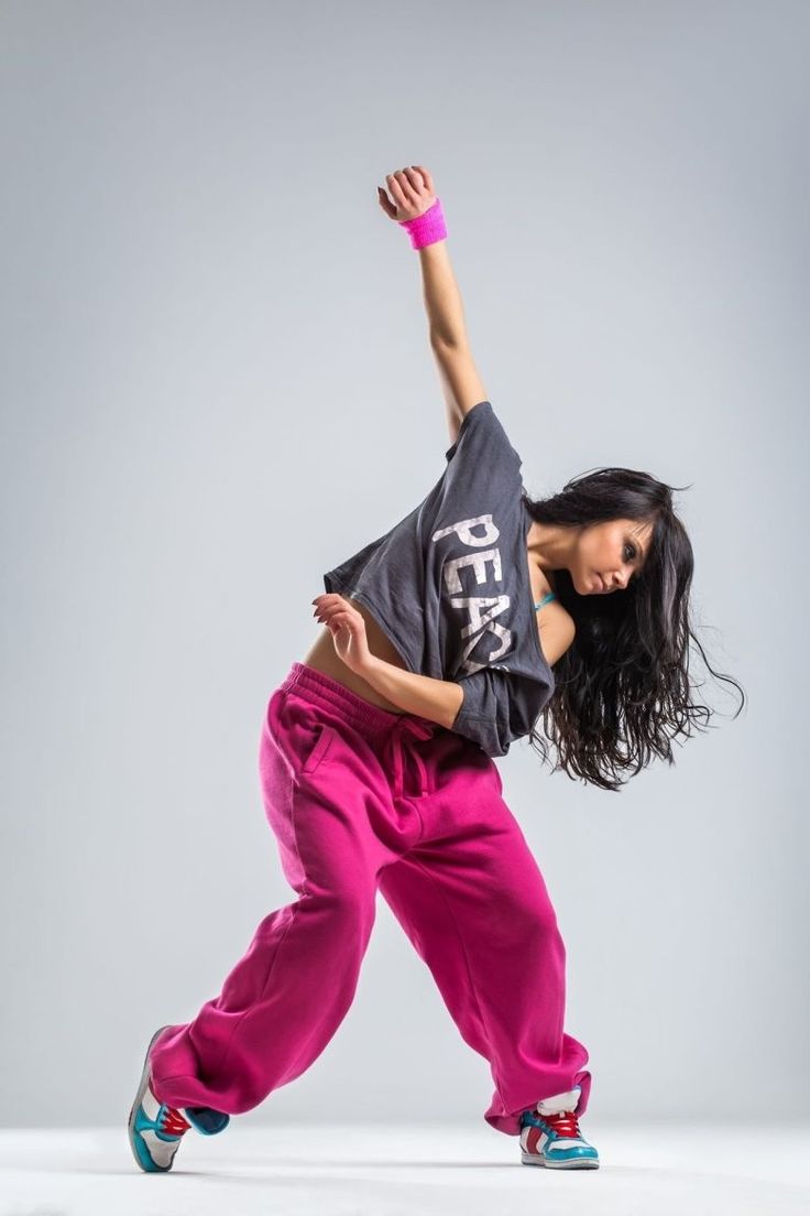 a woman in pink pants and black shirt doing a dance move