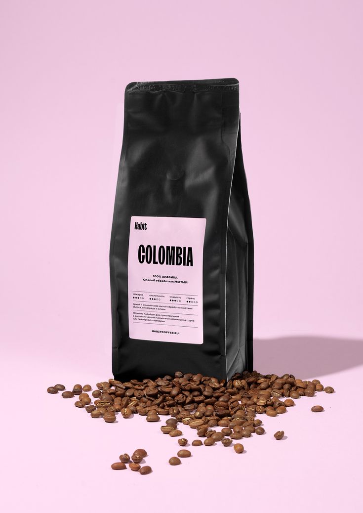 a bag of colombia coffee sitting on top of a pile of beans