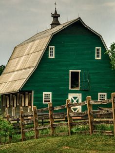 a green barn with a wooden fence around it