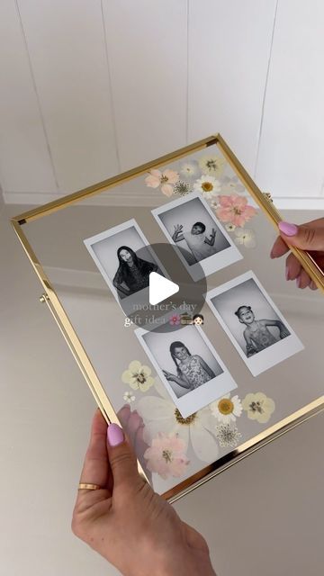 a person holding up a gold frame with photos on it and flowers around the edges