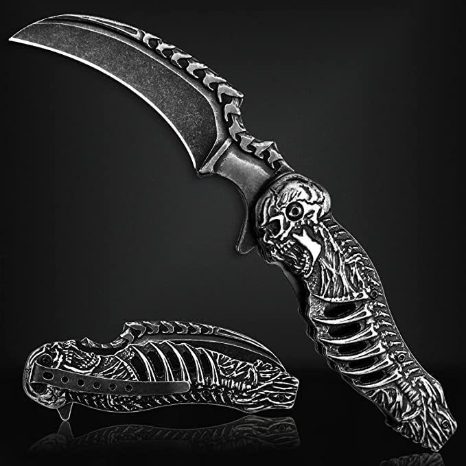 a knife that is sitting on top of a black surface with a skeleton in it