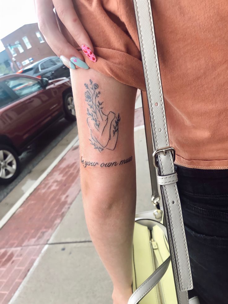 a woman with a small tattoo on her arm holding a yellow purse and looking at the camera