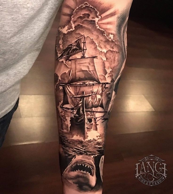 a man's arm with a shark and ship tattoo design on it, done by an artist