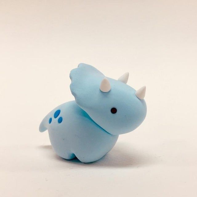 a small blue toy animal with horns on it's head and tail, sitting in front of a white background