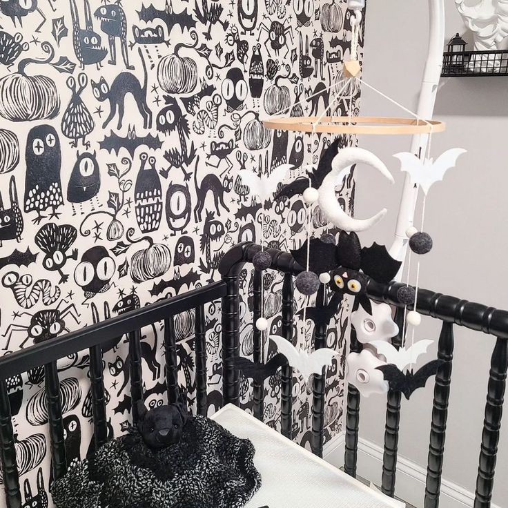 a baby crib with black and white wallpaper on the walls, decorated with halloween decorations