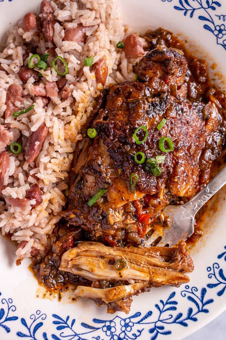 jamaican brown stew chicken on a plate with rice and green onions