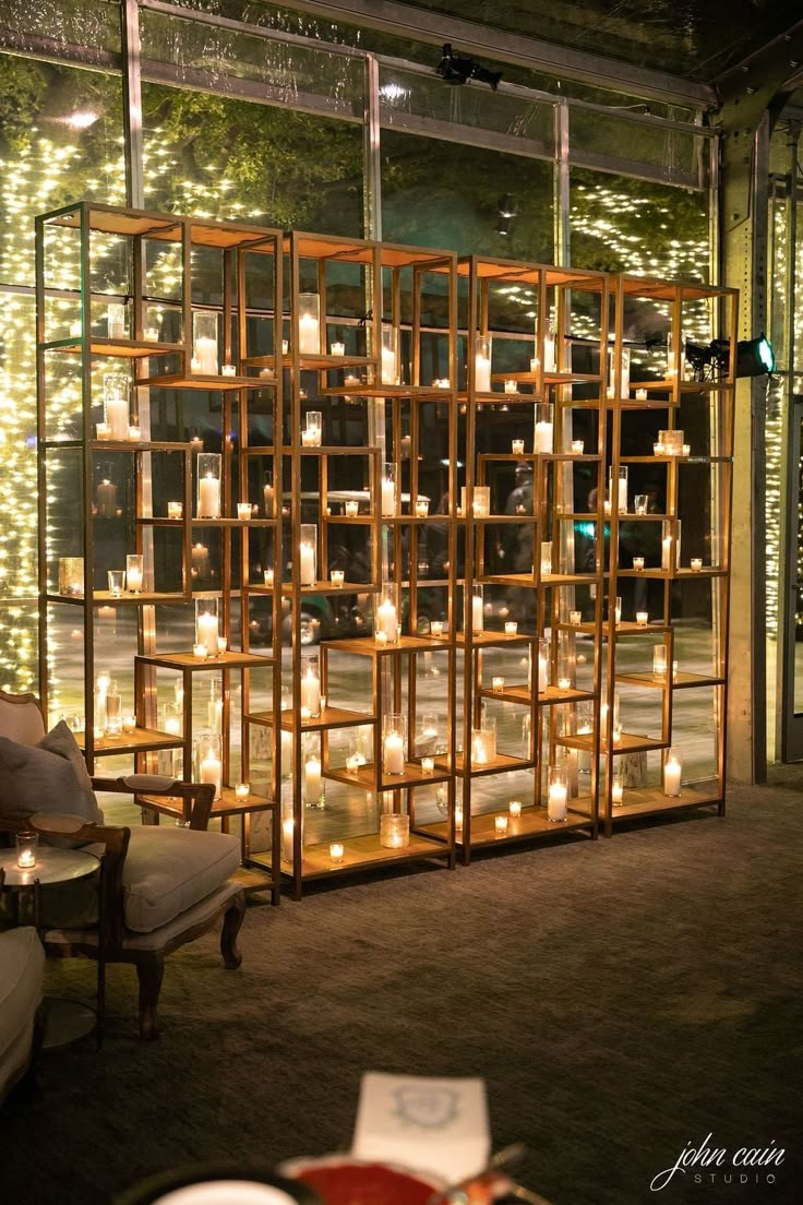 a room filled with lots of lit candles next to a wall covered in bookshelves