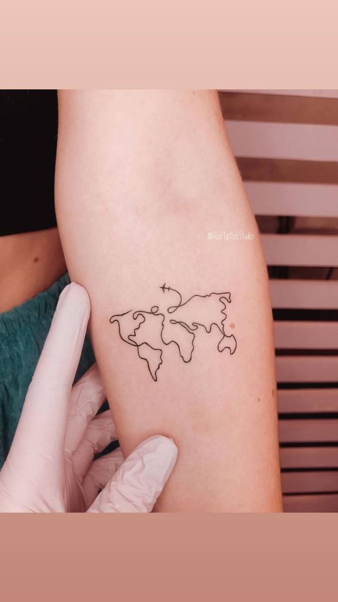 a person with a tattoo on their arm holding a small world map in one hand