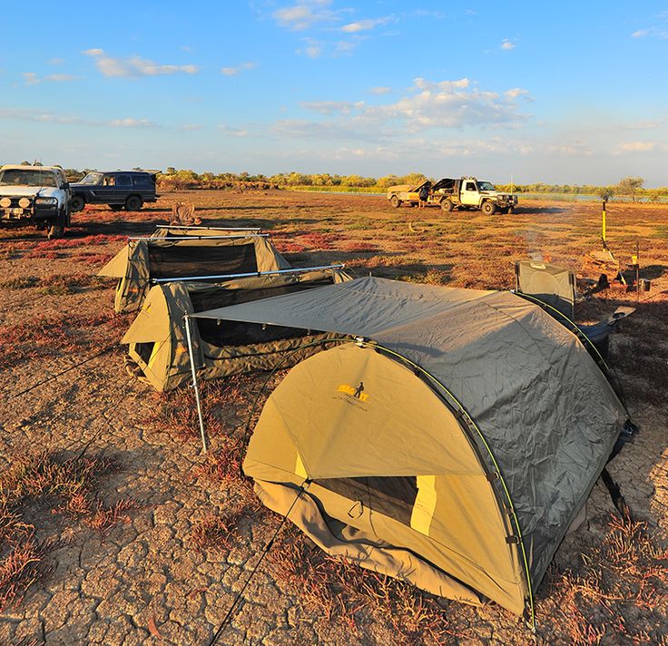 there are many tents set up in the middle of an open field with trucks behind them