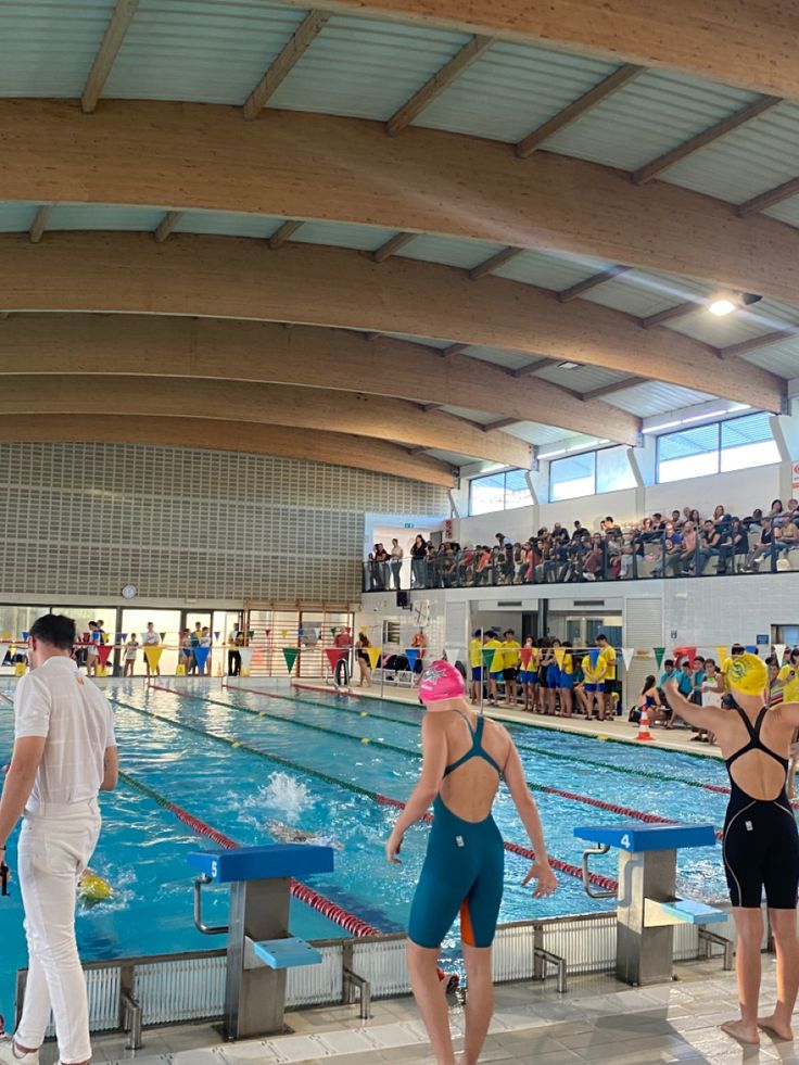 people are standing in the water at an indoor swimming pool