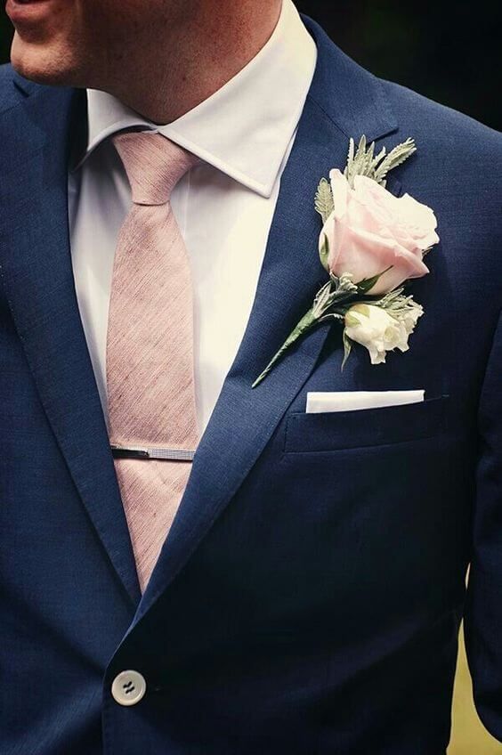 a man in a blue suit with a pink tie and white rose boutonniere