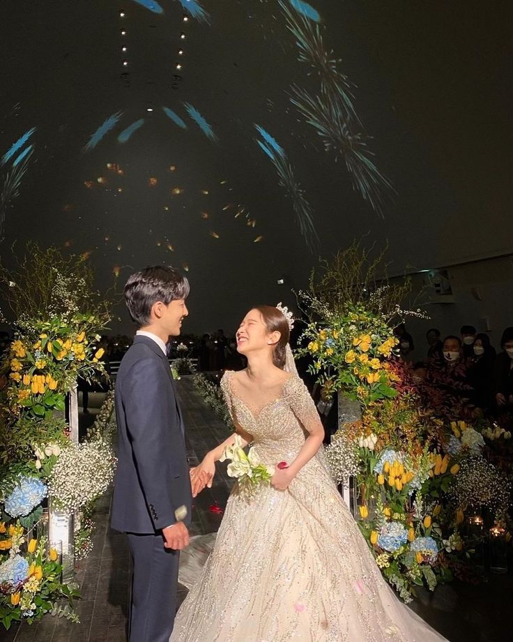 a man and woman standing next to each other in front of a firework display