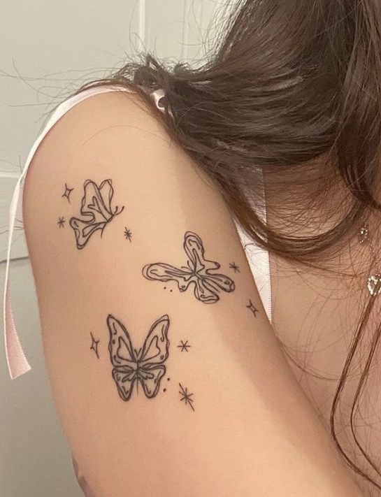 a woman's arm with two butterflies on it and stars in the sky behind her