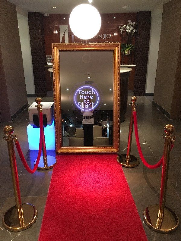 a red carpeted area with a gold framed mirror on the wall and barriers around it