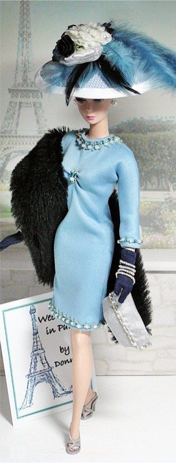 a doll is wearing a blue dress and hat with feathers on it's head