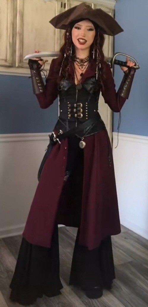 a woman dressed as a pirate holding two swords in one hand and wearing a hat on the other