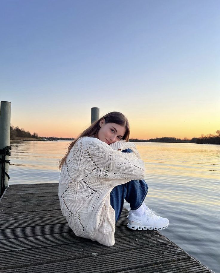 a woman sitting on a dock next to the water