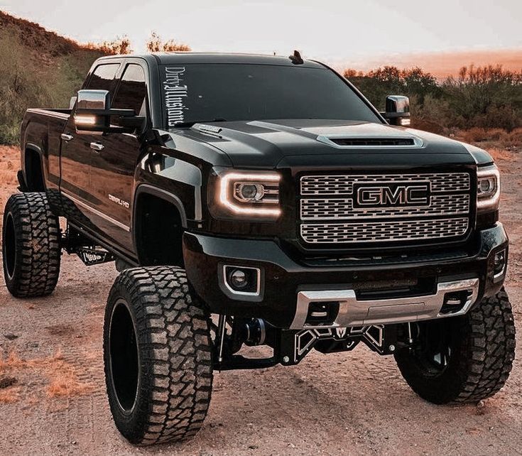 a large black truck parked on top of a dirt road