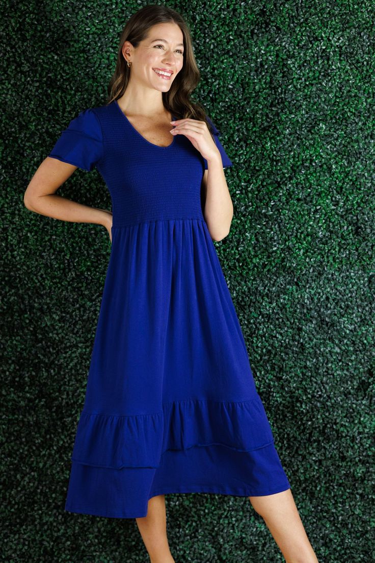 A statement dress that feels as comfortable as loungewear, sign us up! The Mattie Dress is just that and more. The smocking on the chest is so flattering and comfortable that this is going to be our go to dress for everything from vacation to date night. In a classic navy, this piece will last from season-to-season. This dress runs large, we recommend you size down. FAVORITE FEATURES: Smocked Bodice Tiered Flattering V-Neck Ruffle Sleeve Detail Midi Length Casual V-neck Midi Dress With Smocked Back, Beach Dresses With Elastic Waistband And Stretch, Comfortable V-neck Dress For Spring, Summer Midi Dress With Elastic Waistband For Vacation, Summer Midi Dress With Elastic Waistband, Casual Midi Dress With Ruffle Hem, Casual Stretch Midi Dress For Vacation, Casual Smocked Midi Dress With Ruffle Hem, Modest Ruched Midi Dress For Summer