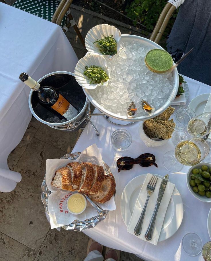 the table is set with bread, wine and other dishes for an outdoor dinner party