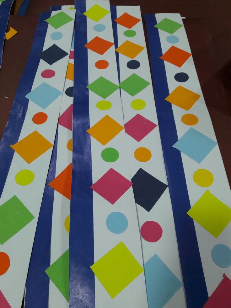 several pieces of paper cut out to look like colorful geometric designs on white and blue strips