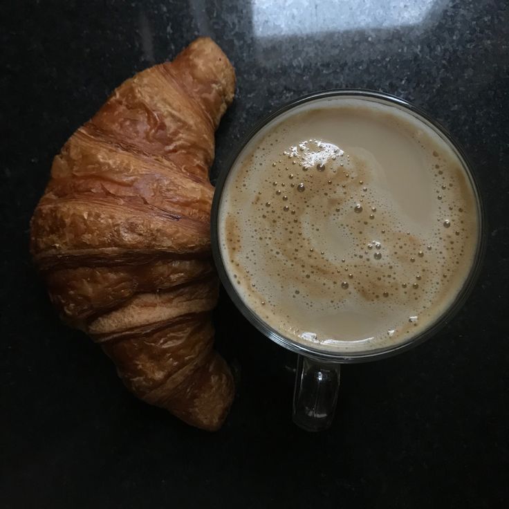 a croissant next to a cup of coffee