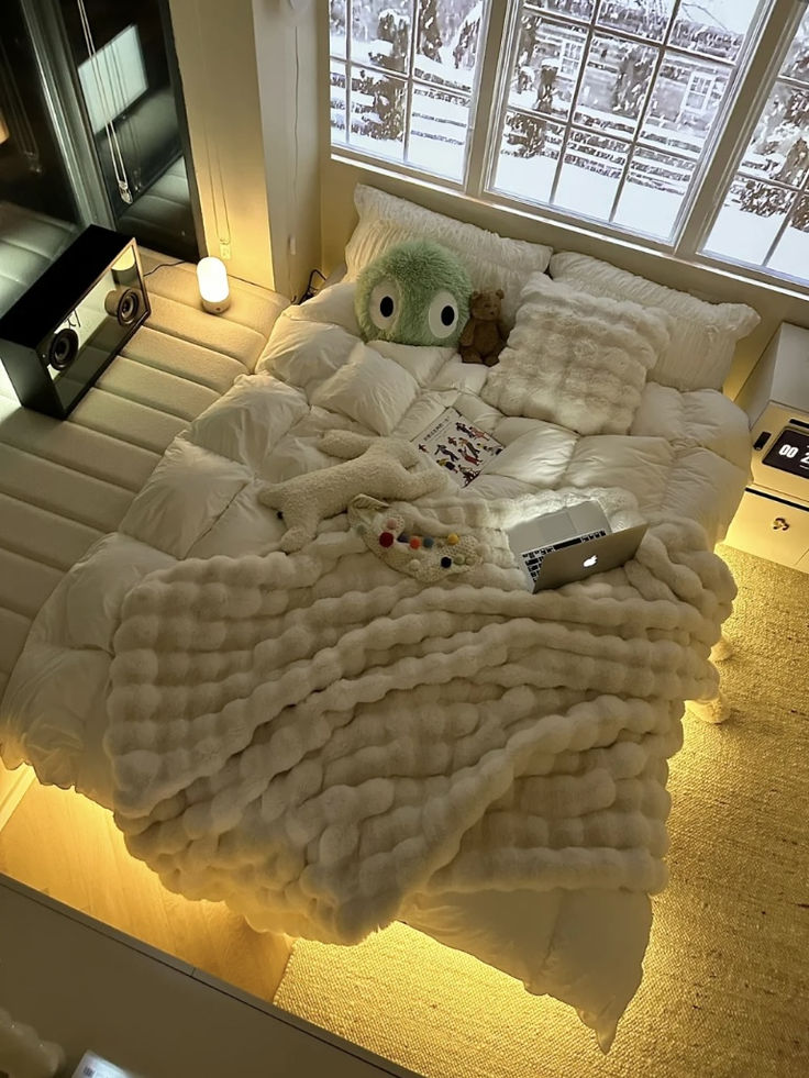 a bed covered in blankets and pillows next to a window