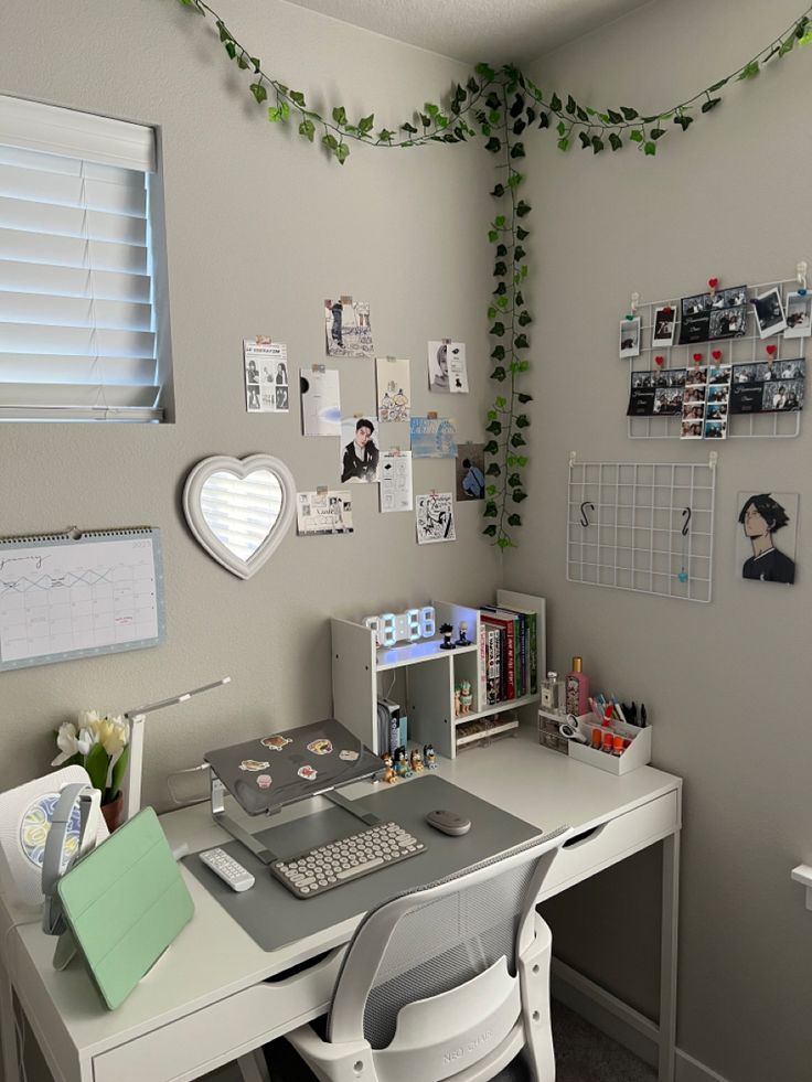 a white desk with a computer on top of it next to a wall covered in pictures