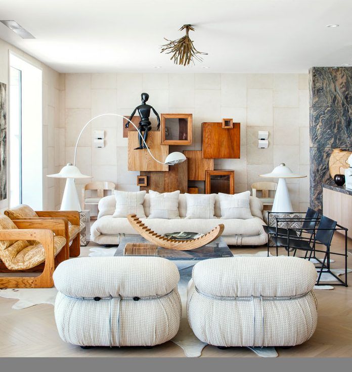 a living room filled with lots of furniture next to a wall covered in art pieces