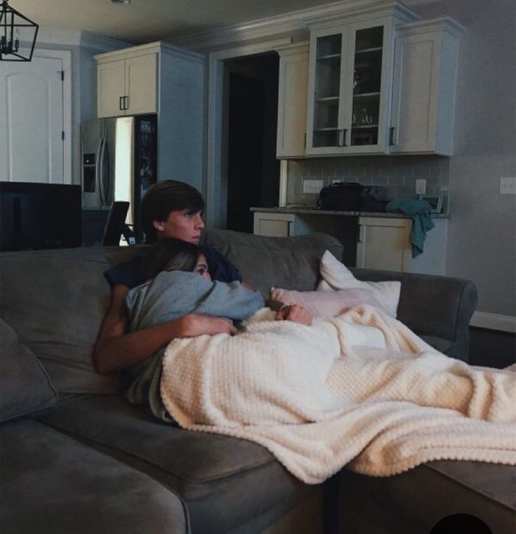 a man laying on top of a couch covered in a blanket