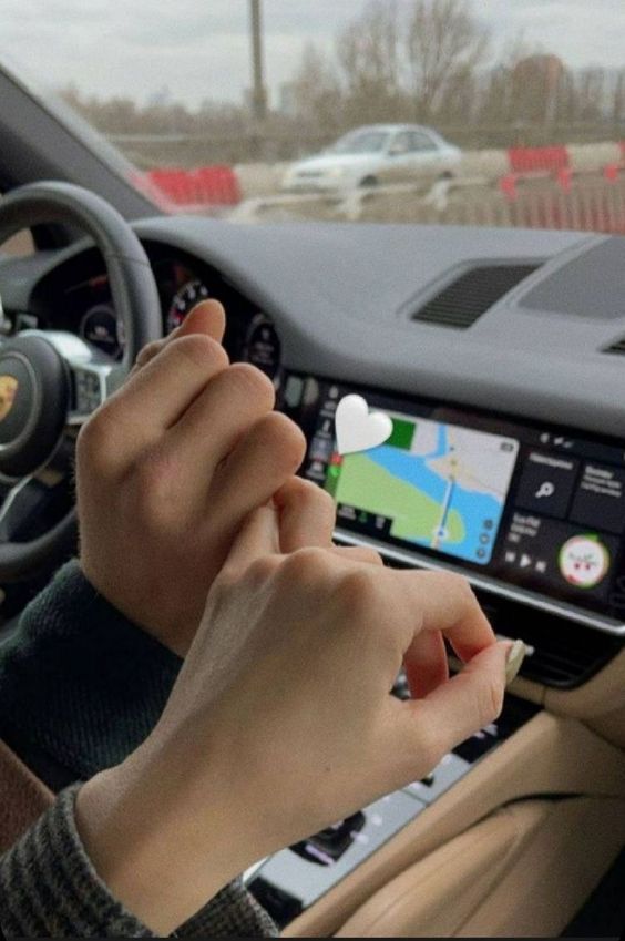 a person driving a car with their hands on the steering wheel while using a gps device