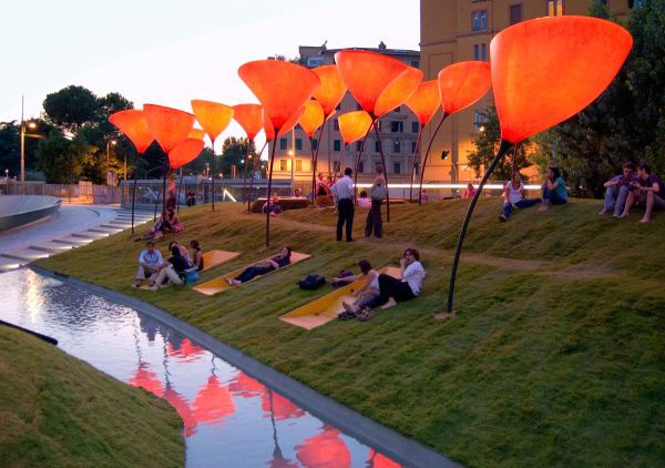 people are doing yoga in the park with orange lanterns floating over them and reflecting in the water