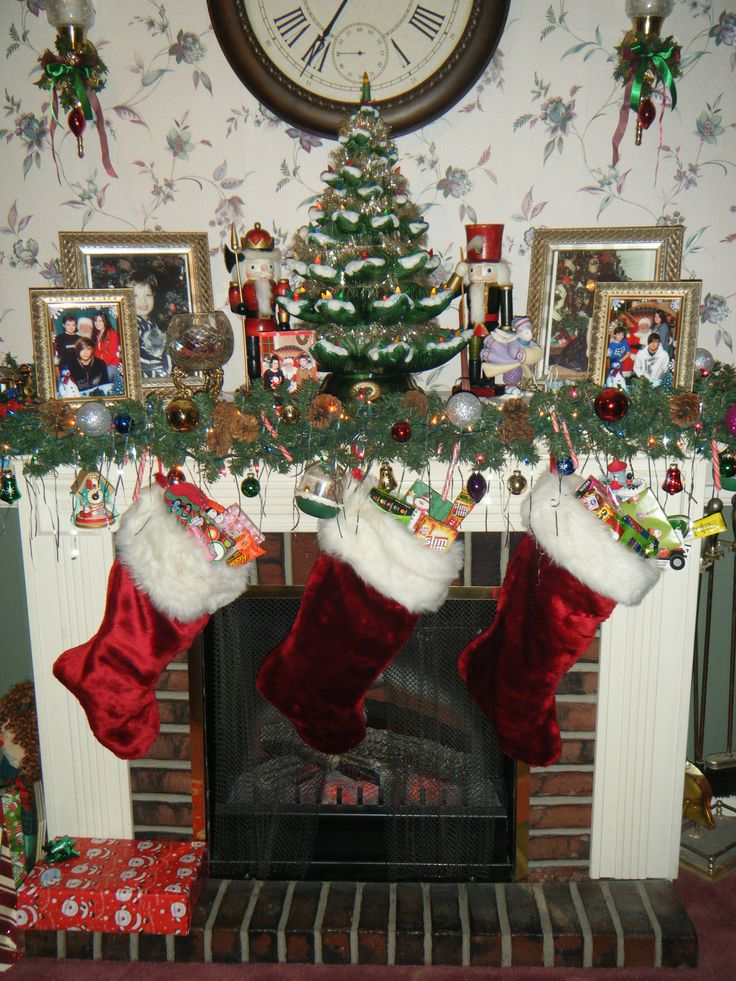 christmas stockings hanging from the mantle in front of a fire place with pictures on it