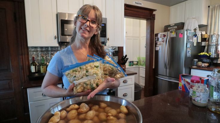 a woman holding a bag of food in her hands while standing next to a pan filled with potatoes