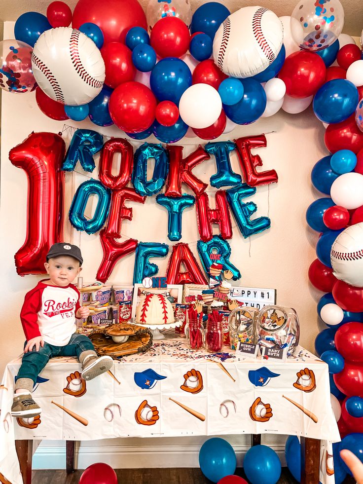 a baseball themed birthday party with red, white and blue balloons on the wall over a table