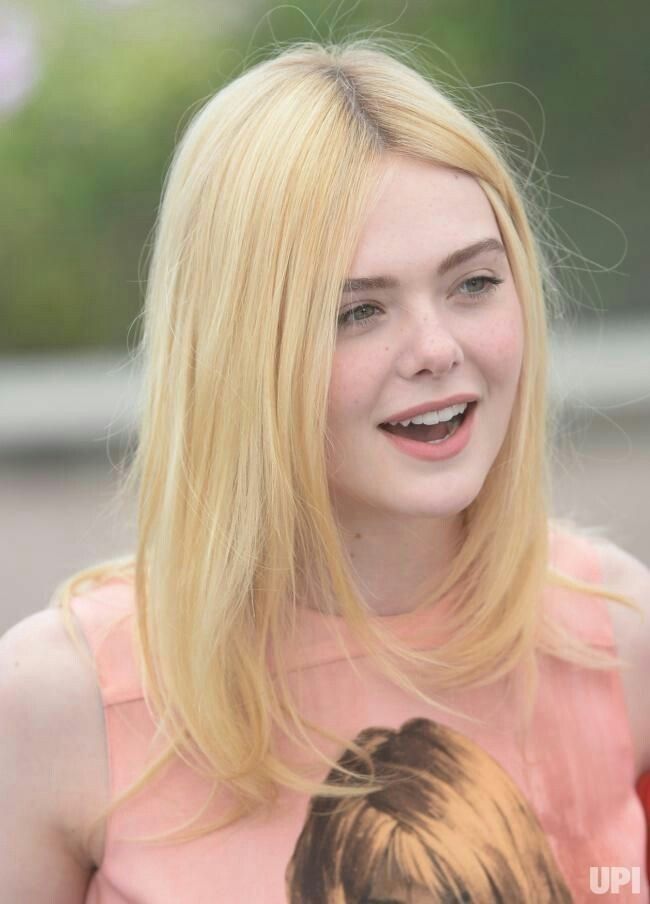 a woman with blonde hair is smiling and looking at the camera while wearing a pink dress