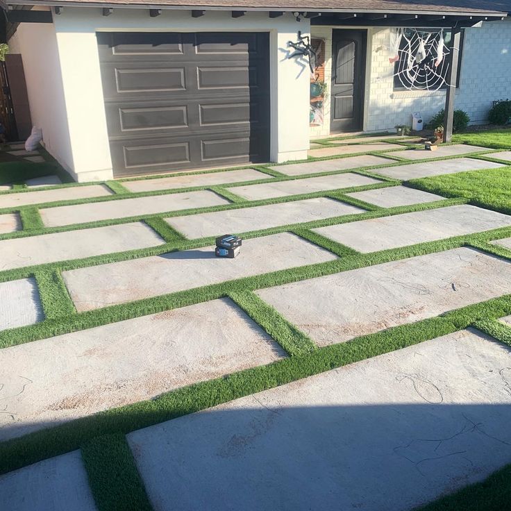 a house with grass on the front lawn and garage in the back yard, as well as an artificial walkway