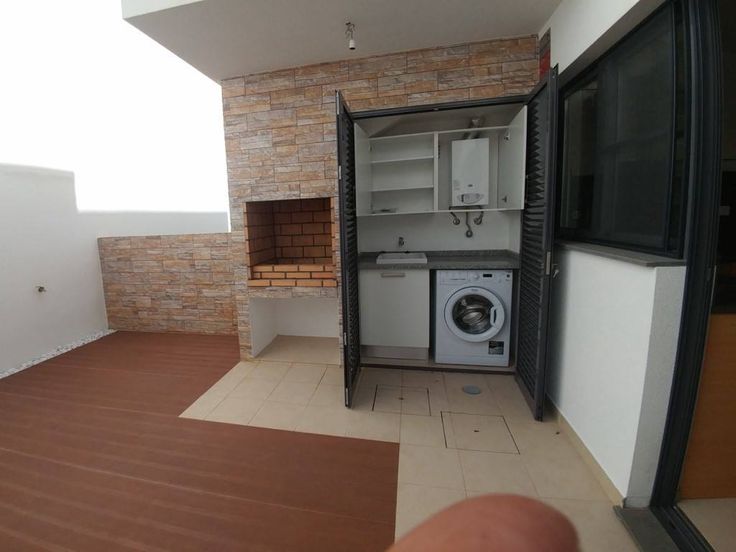 an empty room with a washer and dryer in the door, next to a brick wall