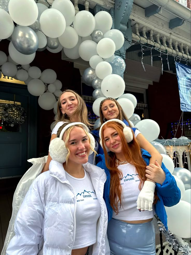 four girls are posing for the camera in front of balloons