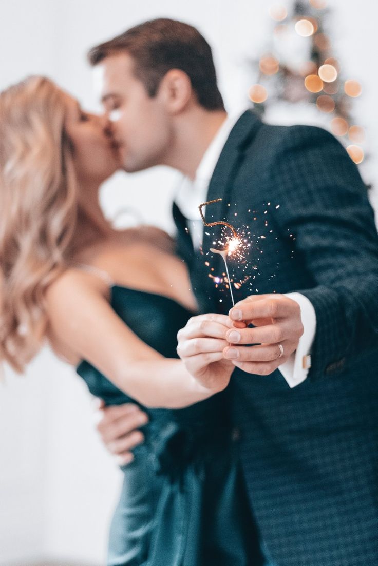 a man and woman kissing while holding sparklers