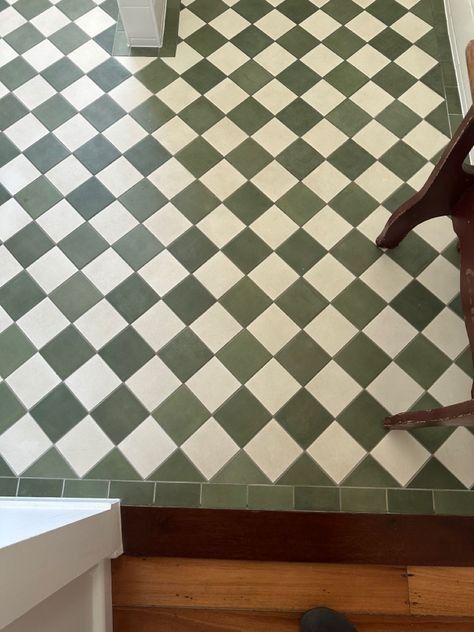 a bird statue sitting on top of a green and white checkered tiled bathroom floor