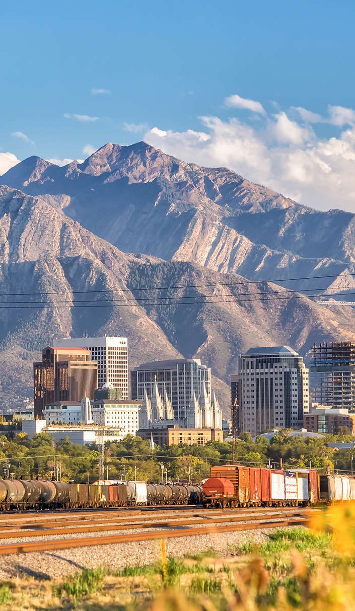 the city is surrounded by mountains in the foreground, with train tracks running through it