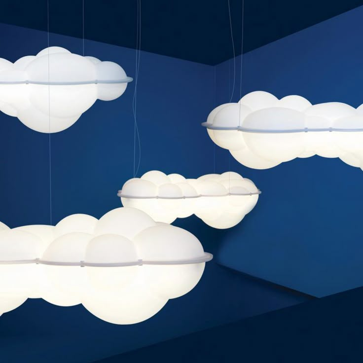 three suspended lights with clouds on them hanging from the ceiling in front of a blue wall