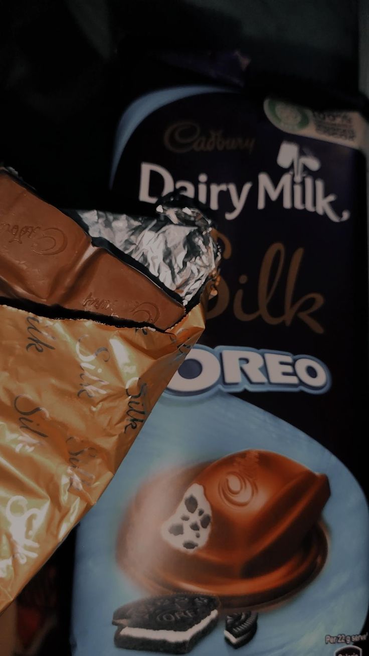 there are chocolate bars wrapped in foil and on top of each other, next to a box of milk