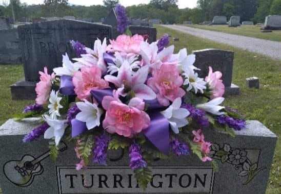 a headstone with flowers and purple ribbons on it