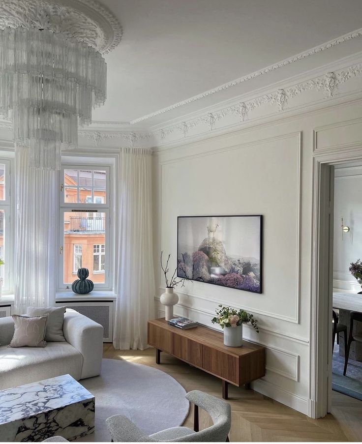 a living room filled with furniture and a chandelier hanging from the ceiling next to a window