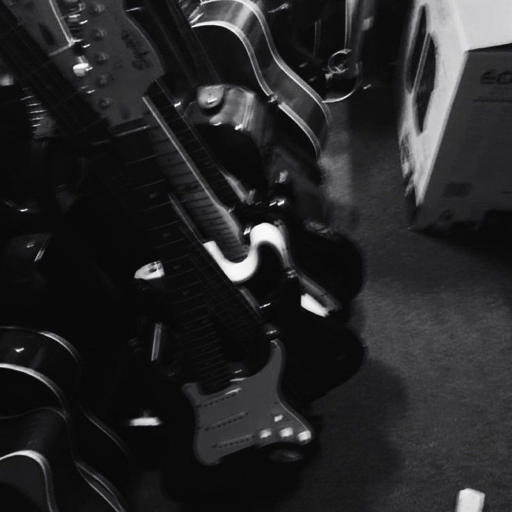 a black and white photo of guitars stacked on top of each other in a room