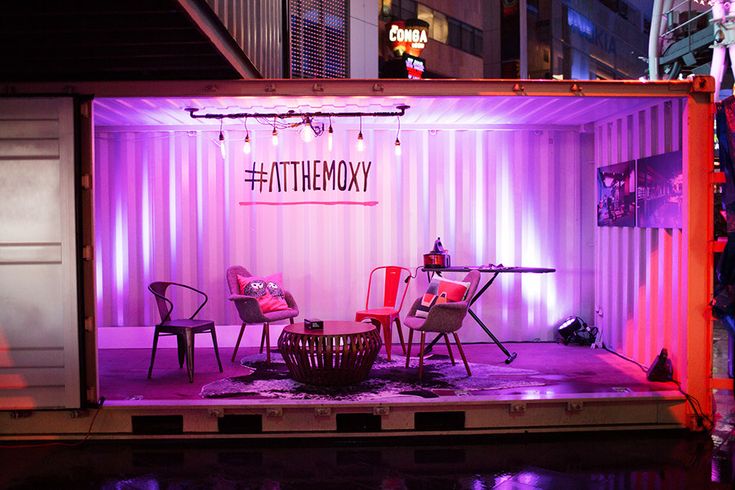 a stage set up with chairs and tables in front of a shipping container at night