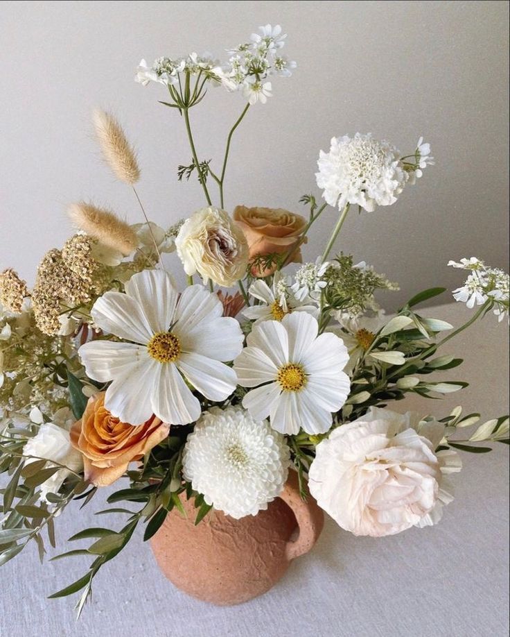 a vase filled with lots of white and orange flowers