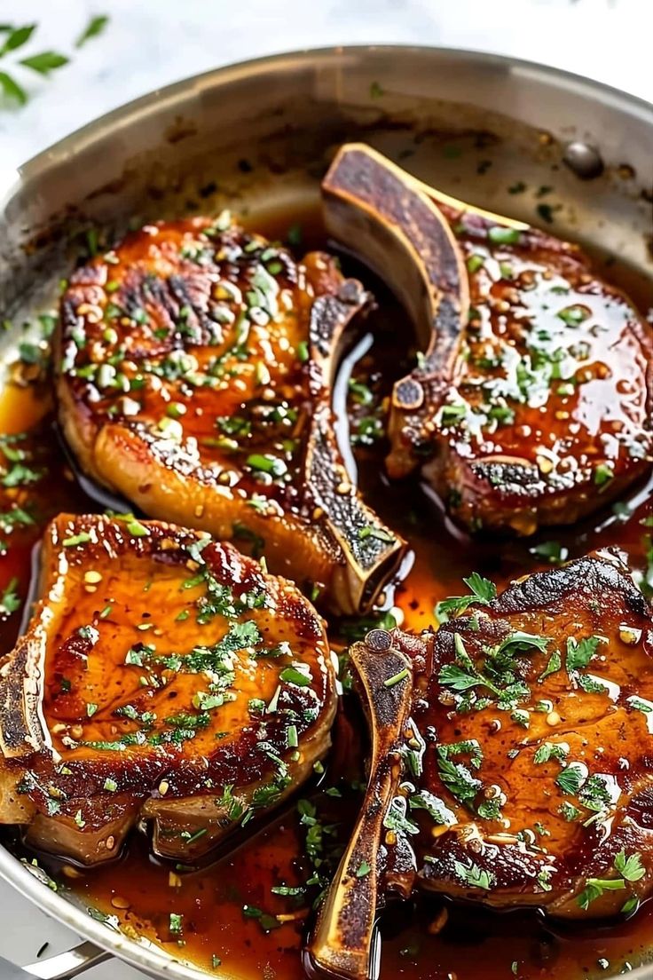 some meat is cooking in a pan with sauce and parsley on the side,